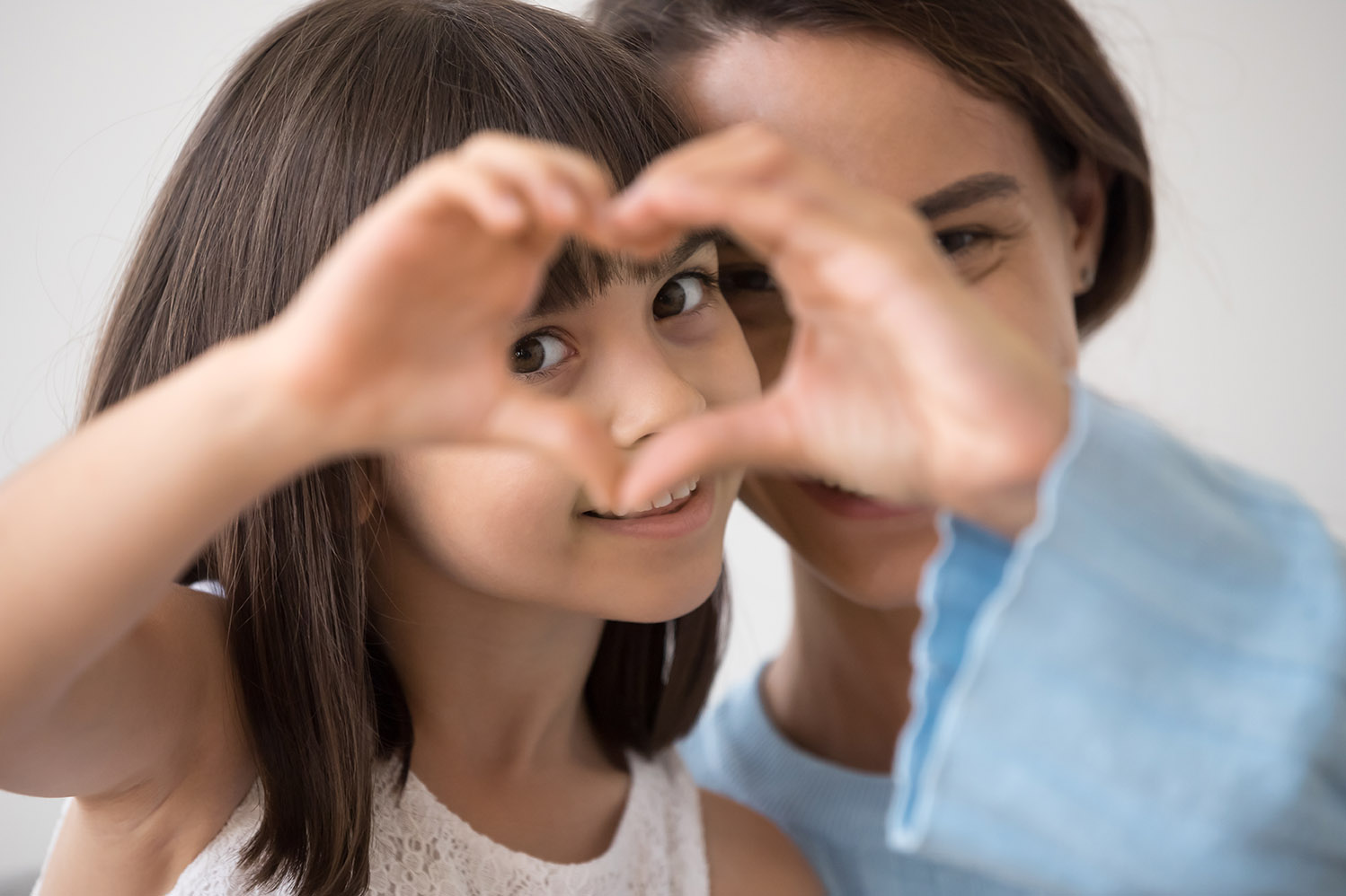 Little girl and mom creating a heart shape to thank donors